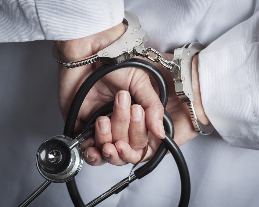 Female Doctor or Nurse In Handcuffs and Lab Coat Holding Stethoscope.